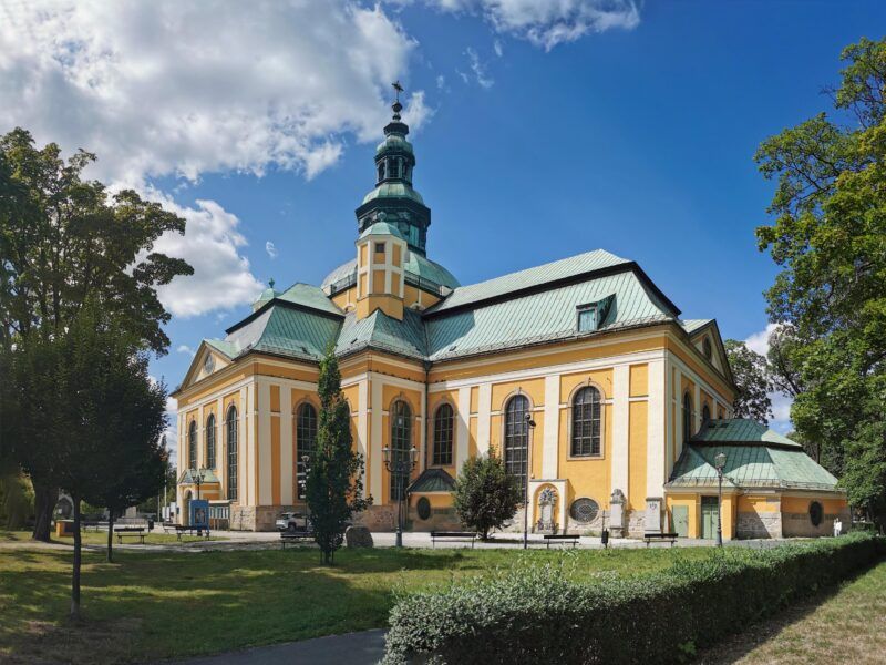Zabytkowy kościół z żółtą elewacją i zaśniedziałym dachem