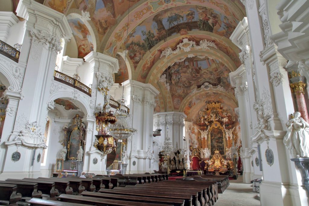 Wnętrze barokowego kościoła, z bogato dekorowanymi złoconymi sufitami