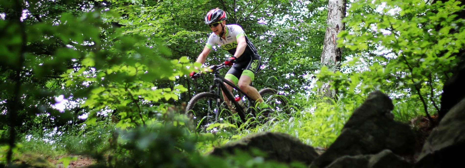 Rowerzysta w kasku na rowerze MTB jadący w nierównym terenie w lesie
