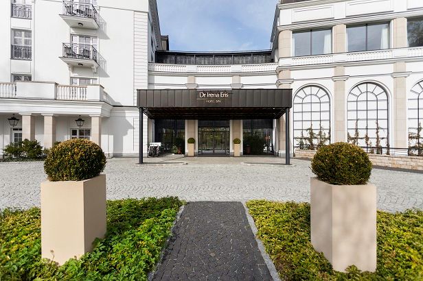 Wejście do eleganckiego hotelu z dwoma kwietnikami na pierwszym planie