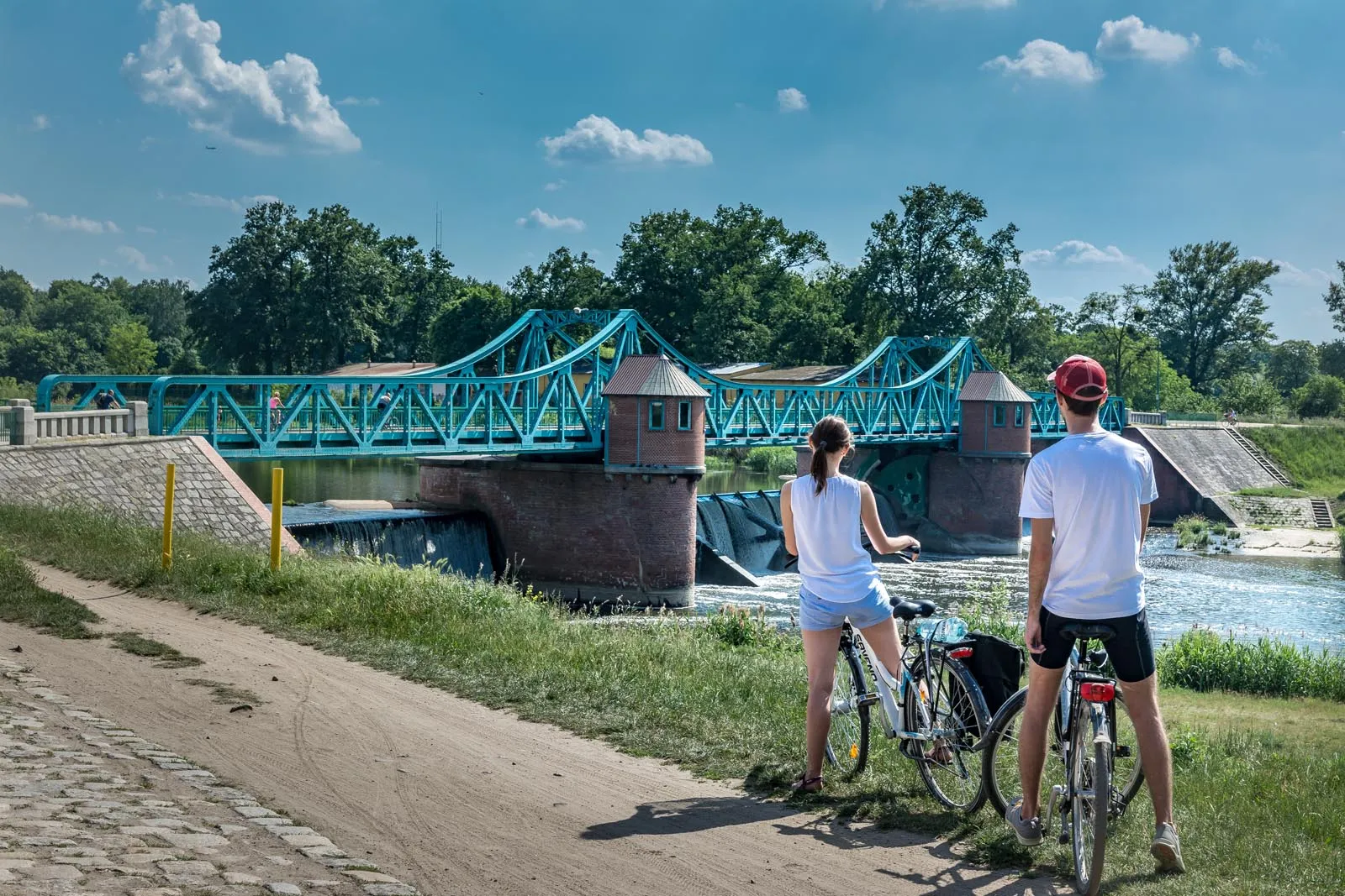 Para rowerzystów na tle zabytkowego jazu