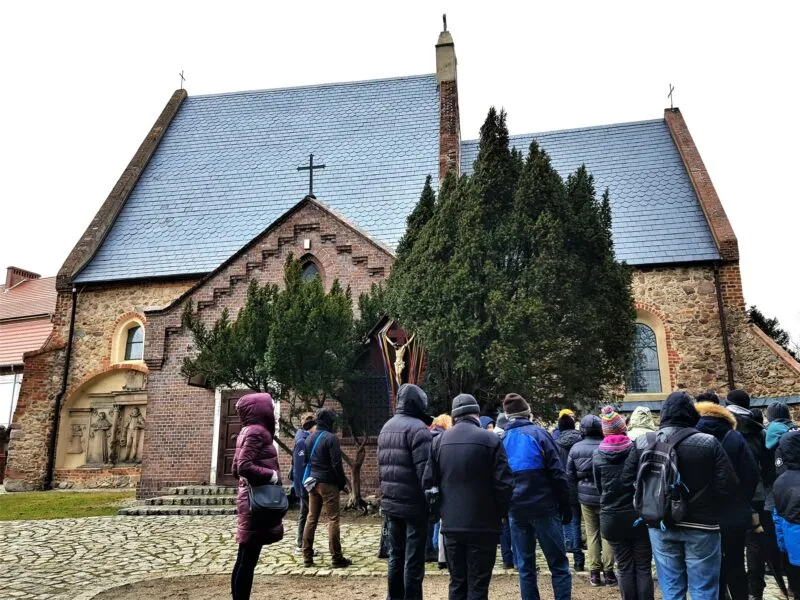 Grupa turystów stojąca przy zabytkowym kościele