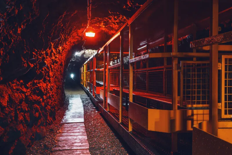Widok na oświetlony korytarz z metalowym wagonikiem podziemnej kolejki