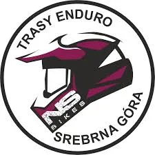 Okrągłe logo Tras Enduro Srebrna Góra zawiera czarno-różowy profil kasku rowerowego oraz nazwę górskiej trasy na białym tle.