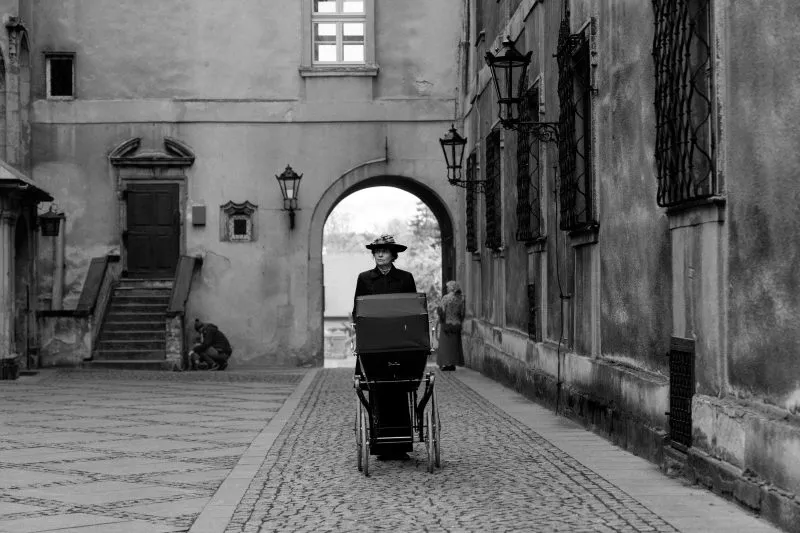 Zdjęcie przedstawia kobietę w historycznym stroju pchając wózek