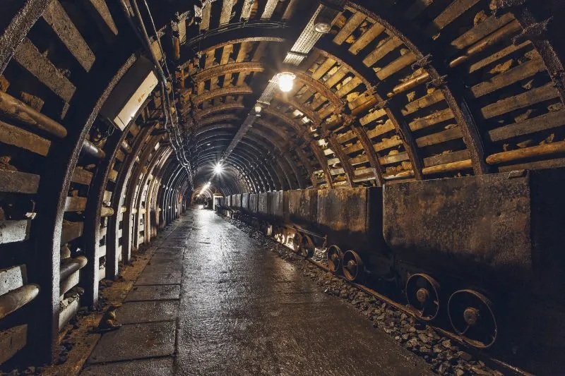 Podziemny korytarz starej kopalni węgla oświetlony sztucznym światłem z widocznymi historycznymi wagonami