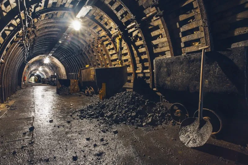 Podziemny korytarz starej kopalni węgla oświetlony sztucznym światłem z widocznymi historycznymi wagonami