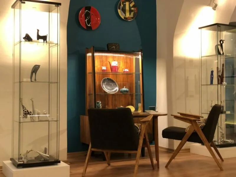Ekspozycja w Muzeum Porcelany w Wałbrzychu. Na zdjęciu witryna z eksponatami stół i dwa krzesła