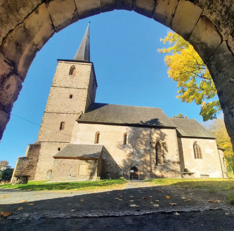 Widok na skąpany w słońcu romański kościół w Świerzawie od strony bocznej z dobrze widoczną wieżą na planie kwadratu