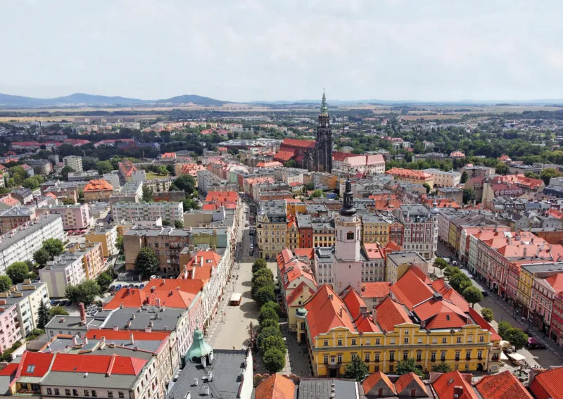 Panorama miasta z lotu ptaka. Wśród budynków wyróżniają się wieże katedry oraz wieża ratuszowa na rynku w Świdnicy.