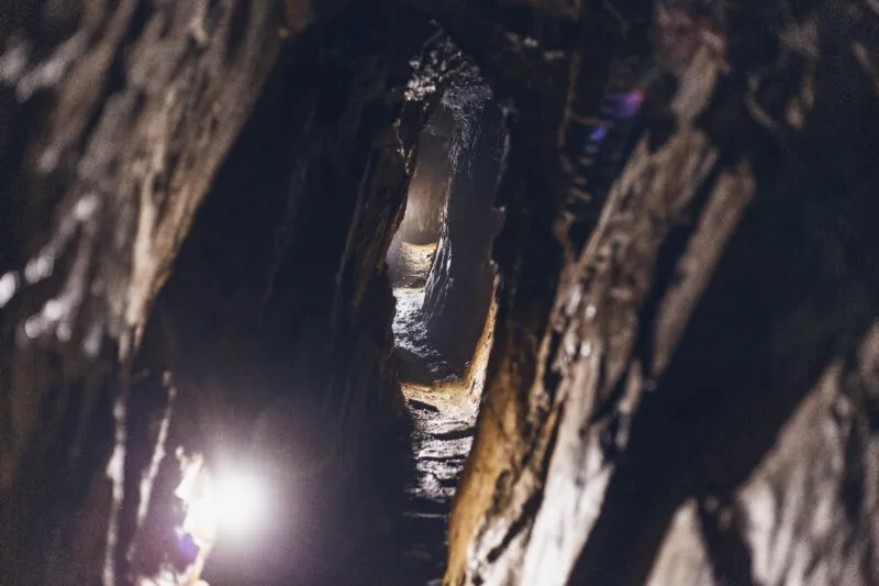 Lekko mroczny tunel wydrążony w skale. Na końcu korytarza lekkie światło.