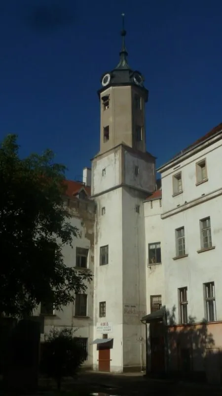 Widok na murowaną, pomalowaną na biało, zabytkową wieżę zamkową na tle błękitnego nieba