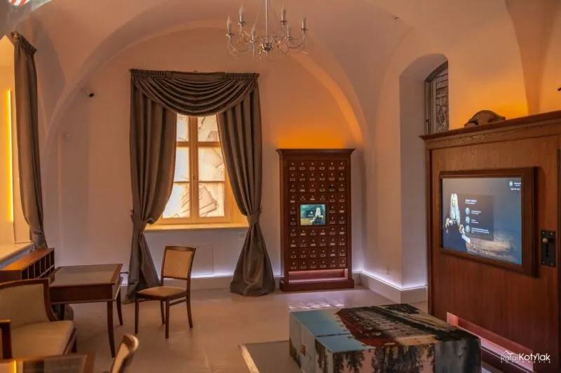 The intimate room of the Nature and Education Center in Sobieszów has a vaulted interior, a touch screen, wooden furniture, and an exhibition under warm light.