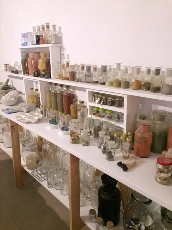 Stoisko laboratoryjne z probówkami, moździerzami i flakonami wypełnionymi barwnikami. 