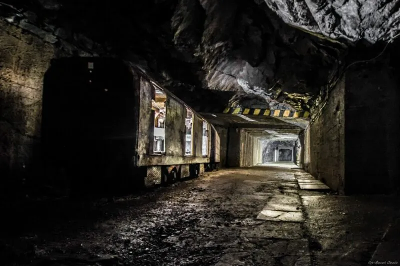 narysowany obraz o gładkich konturach przedstawiający średniej długości tunel z białymi elementami oraz po lewej stronie znajduję się wagon