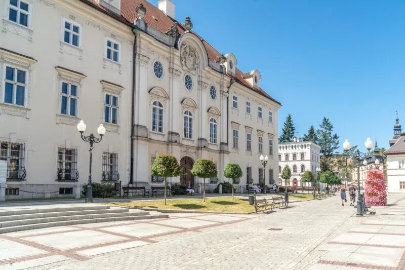 Pałac z jasną elewacją oraz czerwonym dachem, w tle błękitne niebo.