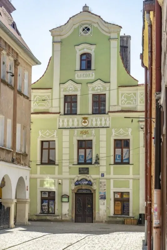 Budynek z biało-zieloną elewacją, w tle niebieskie niebo.