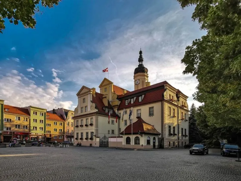 Widok na ratusz, otoczony budynkami, w tle niebieskie niebo.