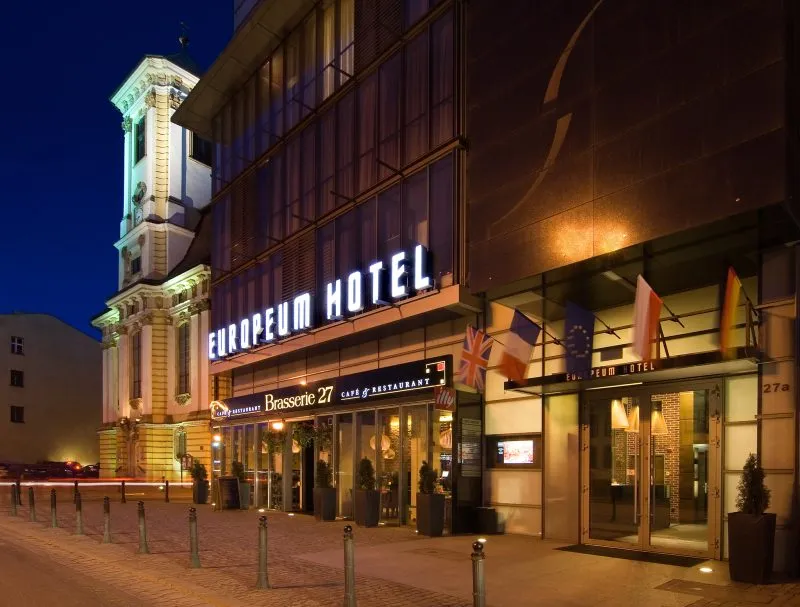 Wnętrze do przeszklonego hotelu z napisem Europeum Hotel nad wejściem