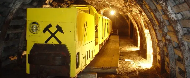 Żółte wagony kolei podziemnej stojące w oświetlonym tunelu.