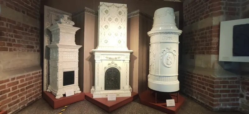 Zbiór tradycyjnych białych pieców ceramicznych, pięknie zaprojektowanych z detalami ozdobnymi i dekoracyjnymi elementami.