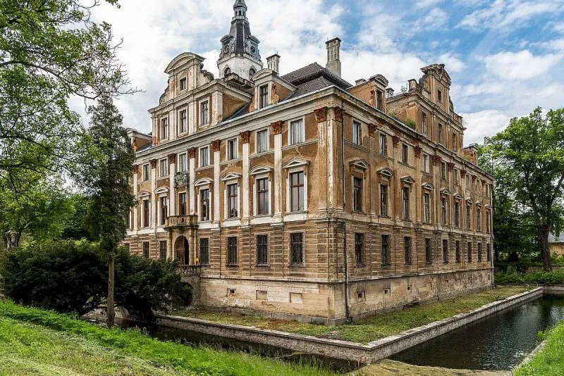 widok na budynek z wieloma oknami, otoczony fosą