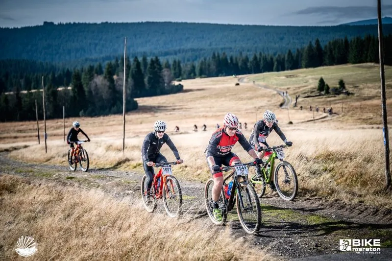 Na zdjęciu rowerzyści ścigają się podczas wyścigu rowerowego z górami oraz karkonoską polaną w tle