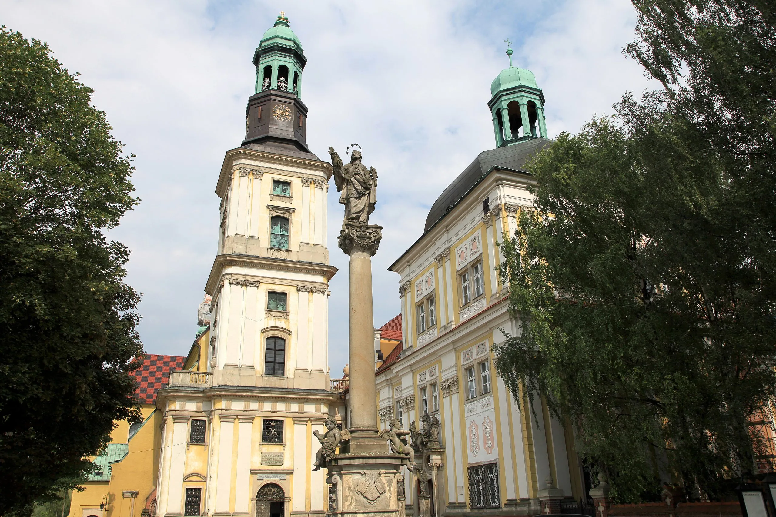 Zdjęcie przedstawia budynek klasztoru i kościoła z kolumną na pierwszym planie